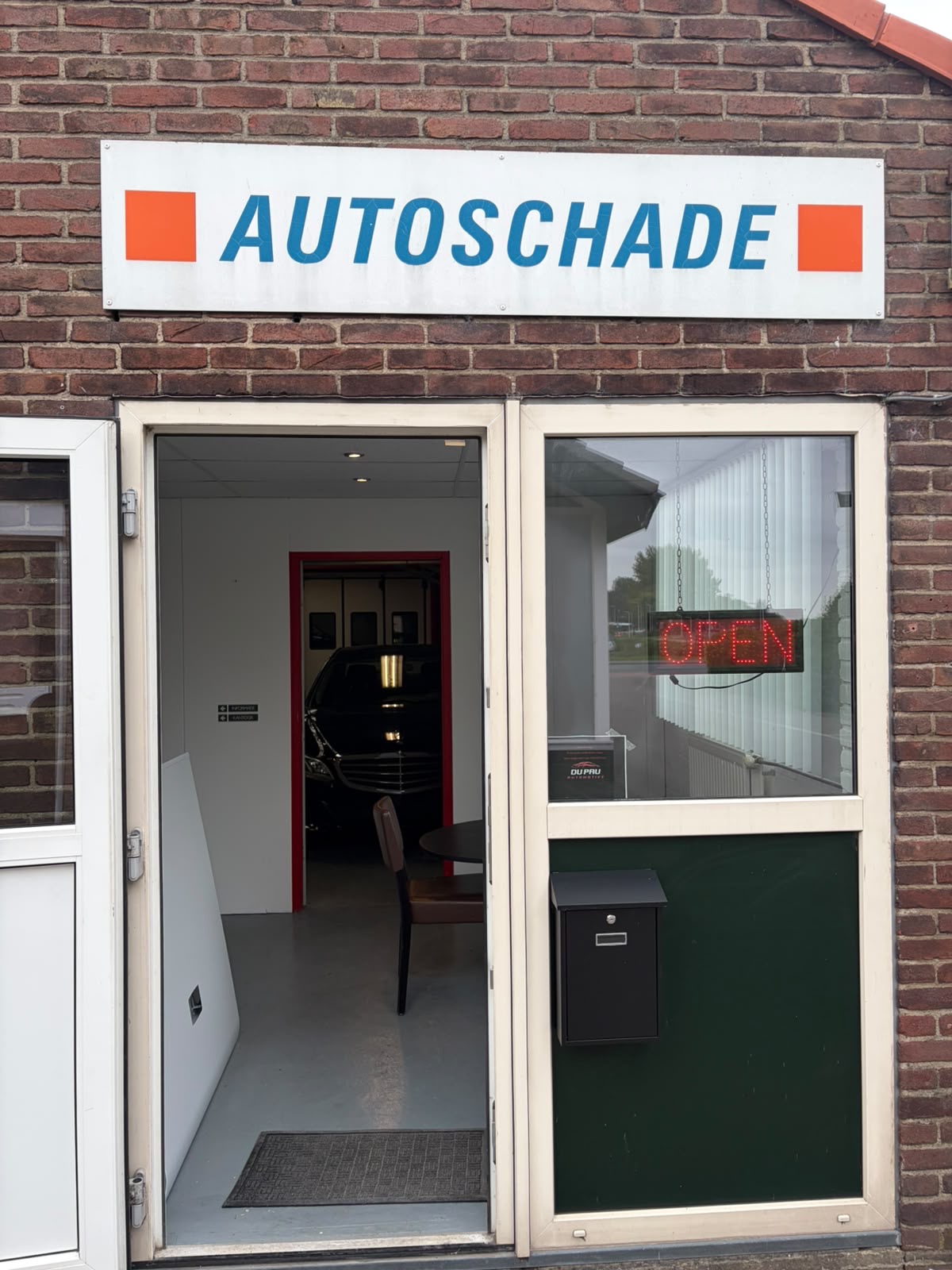 De ingang van DuPau met de geopende groene deur en zicht op de werkplaats