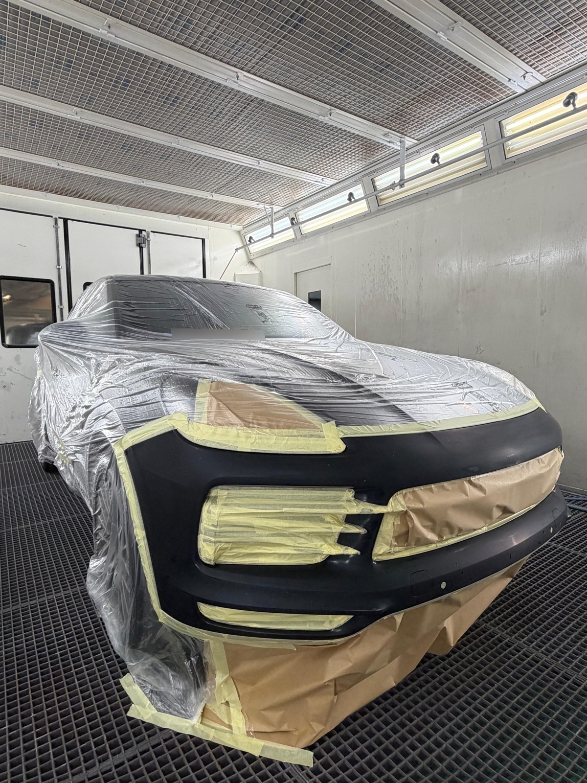 Porsche met voorbereide voorbumper, klaar om te spuiten; de rest van de auto is afgeplakt